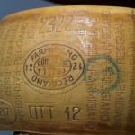 A WHEEL OF PARMIGIANO-REGGIANO CHEESE READY FOR THE MARKET WITH THE GREEN STAMP AND OVAL PARMIGIANO REGGIANO CONSORZIO TUTELA IMPRINT一轮准备上市的PARMIGIANO-REGGIANO奶酪，上面带有绿色的印章和椭圆形的PARMIGIANO-REGGIANO CONSORZIO TUTELA的印章
